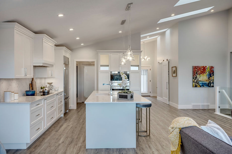 A stunning kitchen area hanging lights, a large fridge and some wall art.