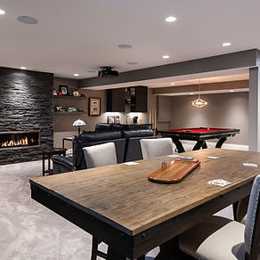 A fantastic basement renovation in Calgary, Alberta. with a pool table, stunning lighting, and a large table. Renovated by Dependable Renovations.